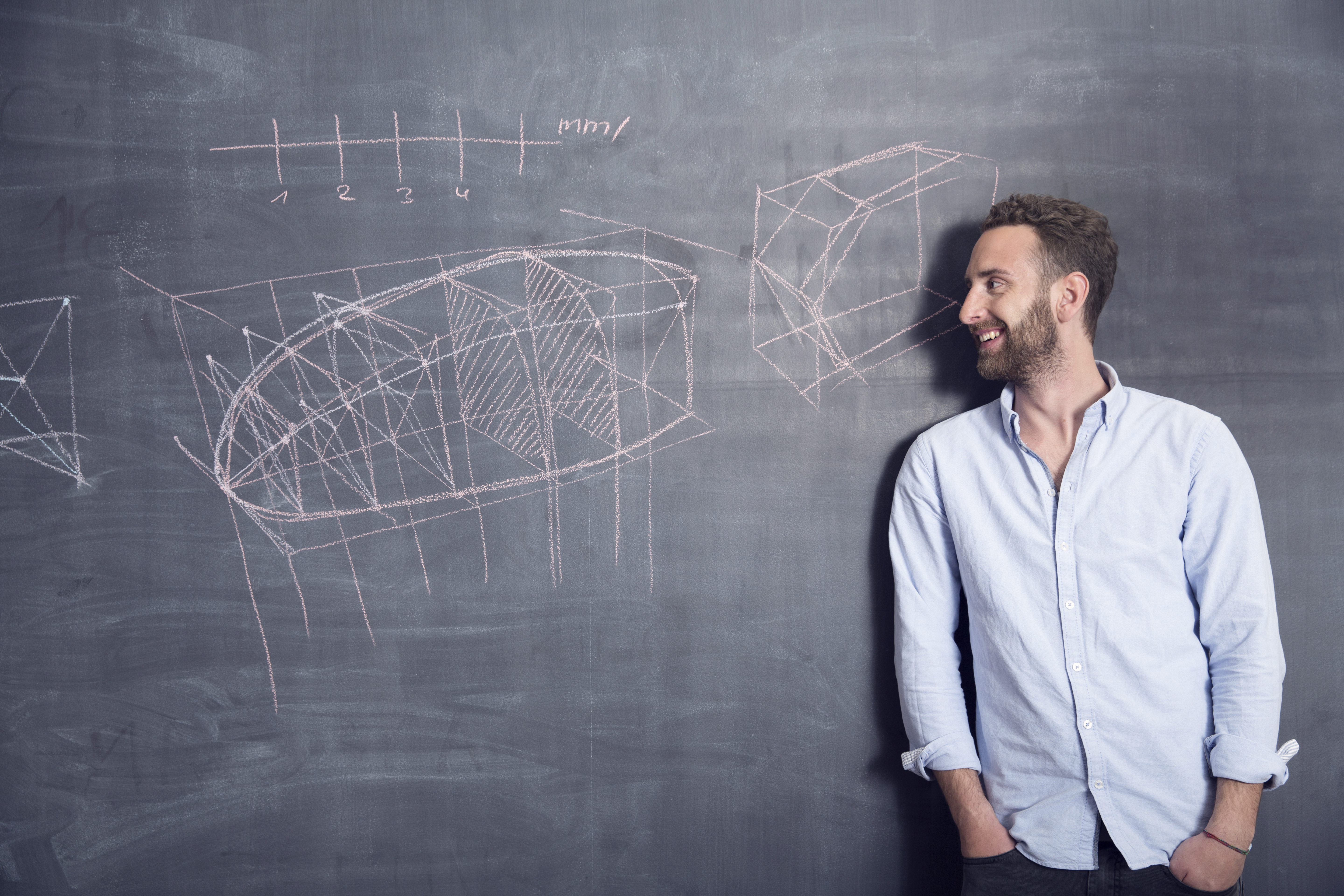 Young man looking at drawing at blackboard