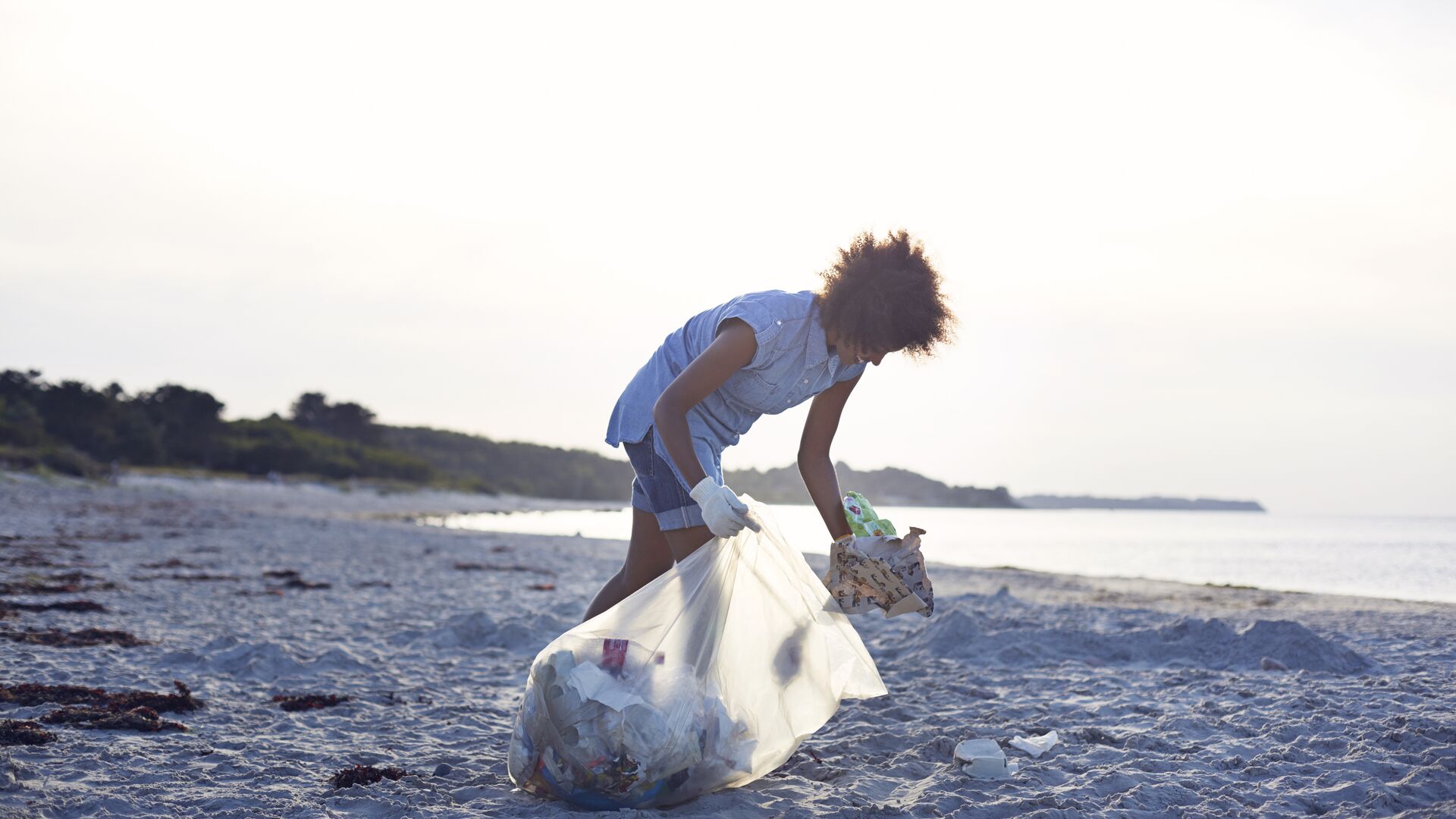 Young woman collecting trash on beach