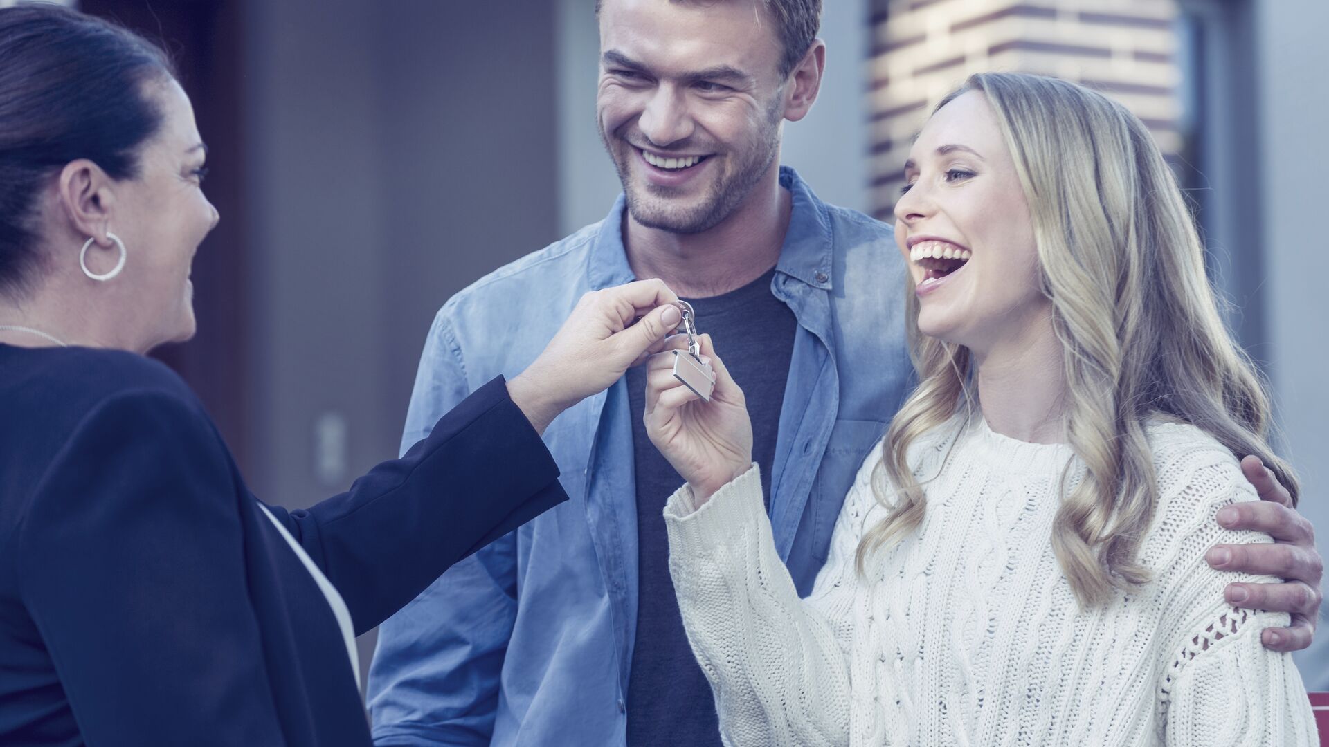 Couple standing in front of a new home with agent