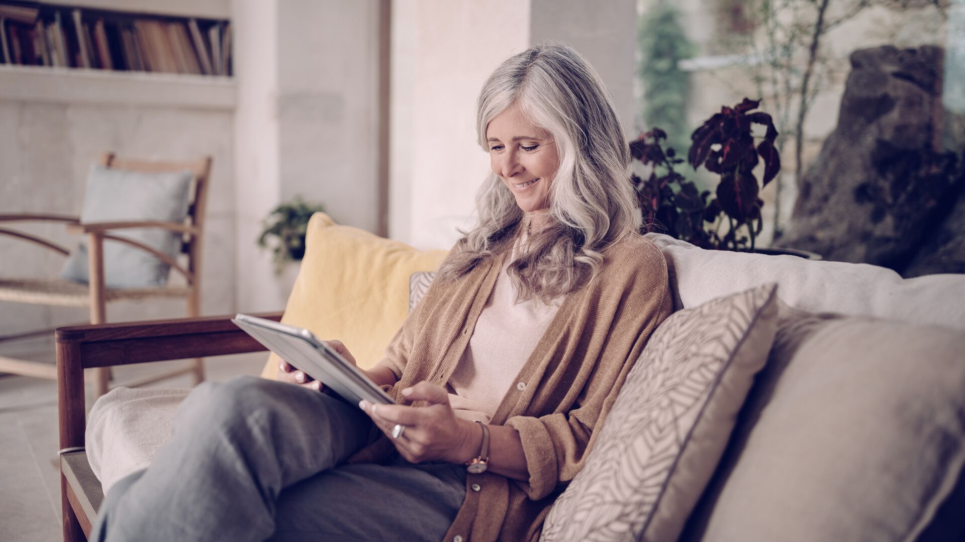 Senior woman sitting in couch with tablet