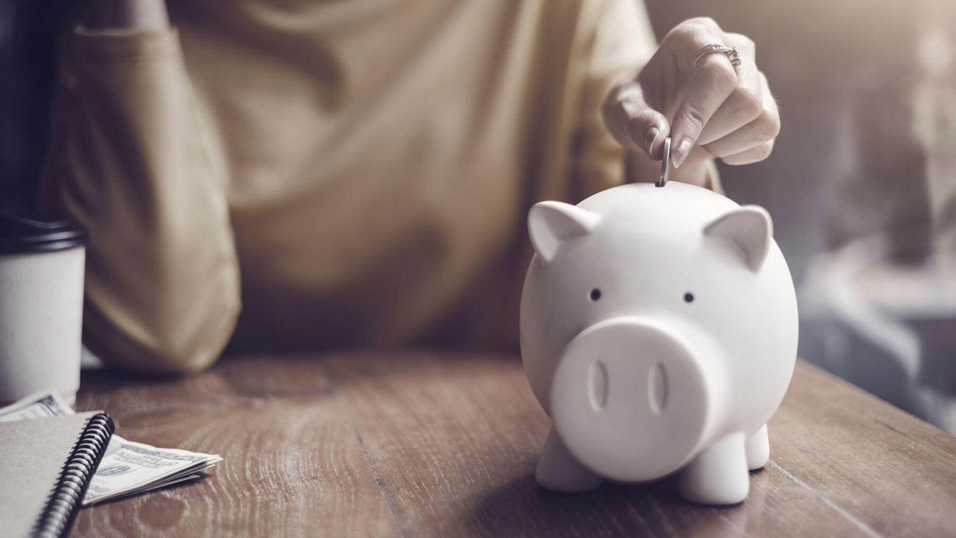 woman-putting-coin-in-piggy-bank