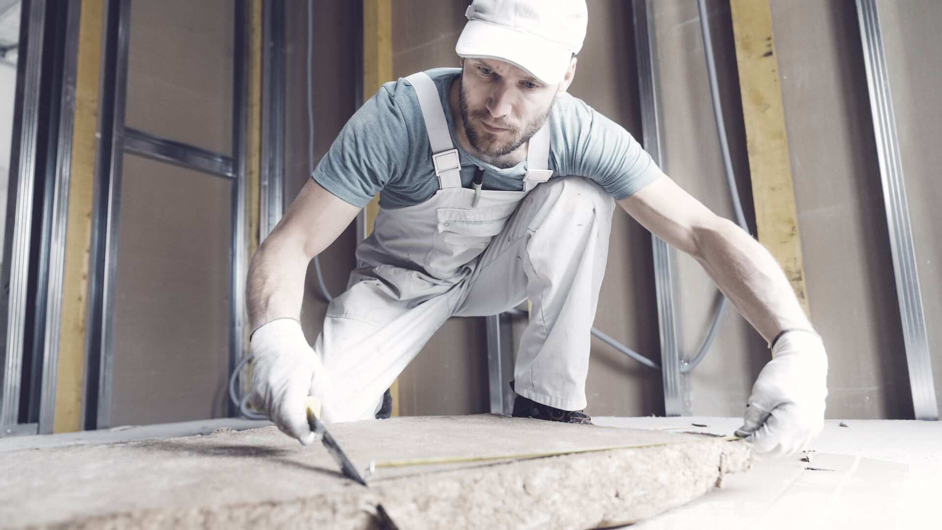 Construction worker cutting mineral rock wool