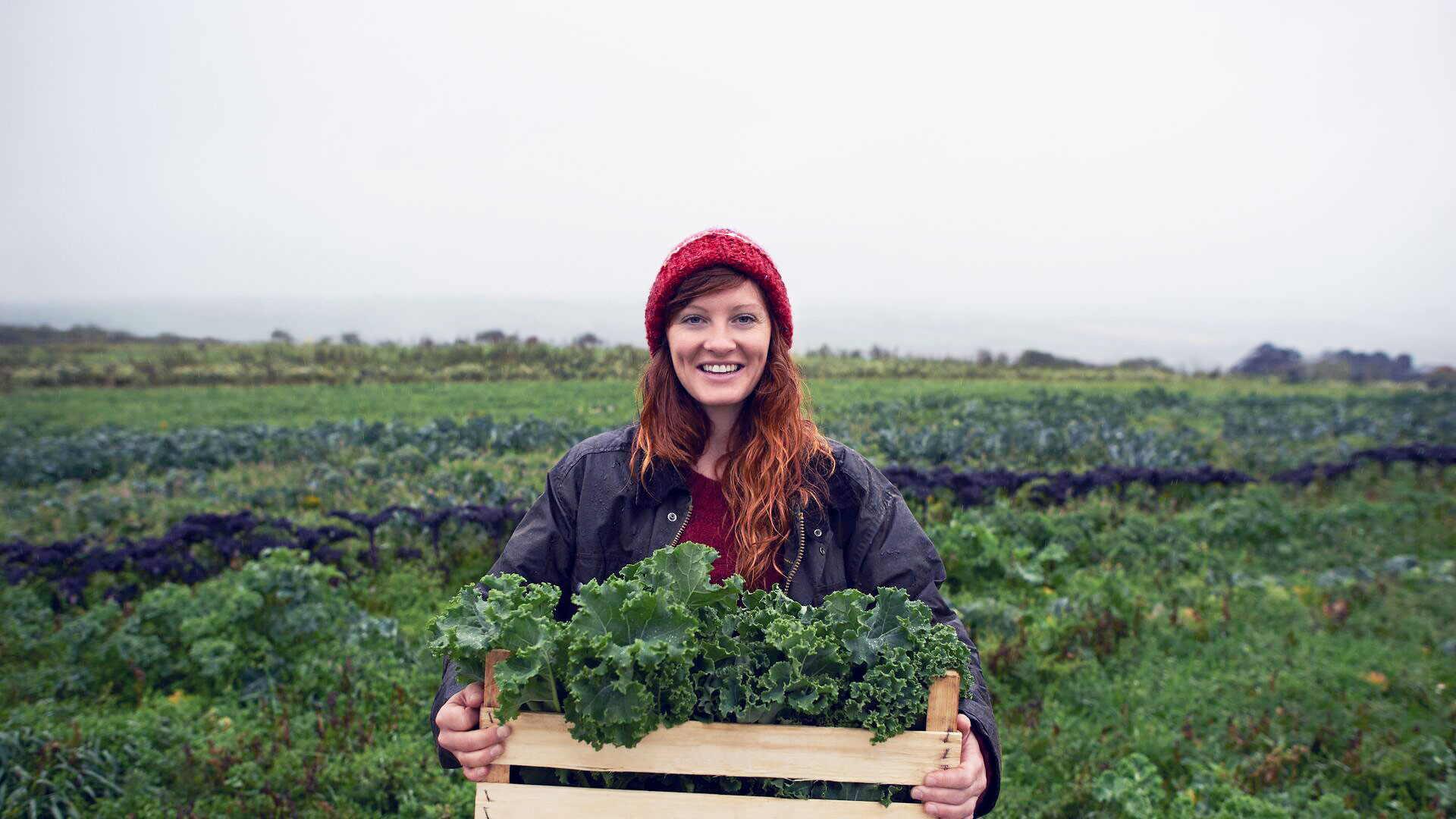 Smiling young woman holding greens on farm