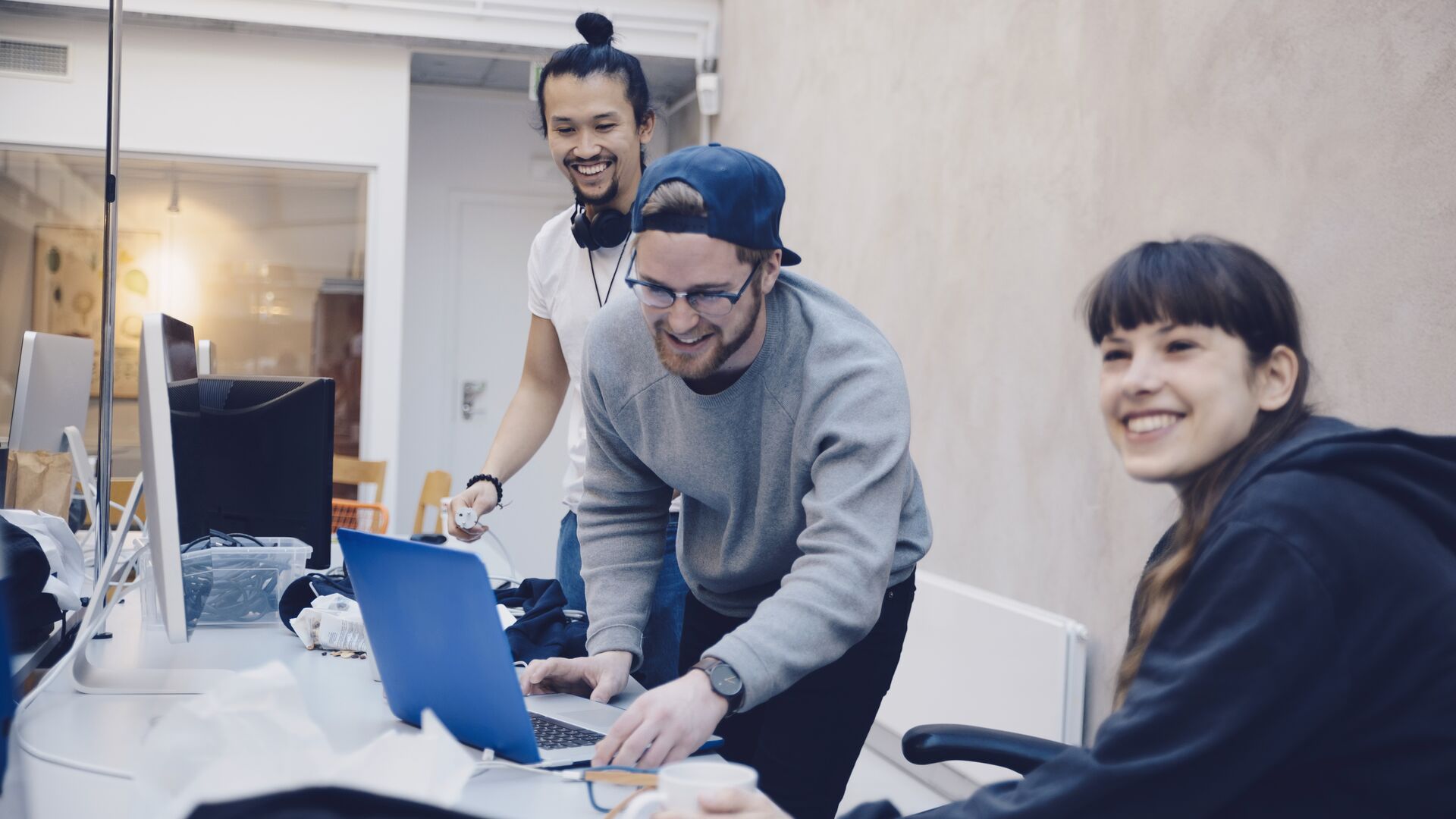 Happy male and female computer programmers at desk in office