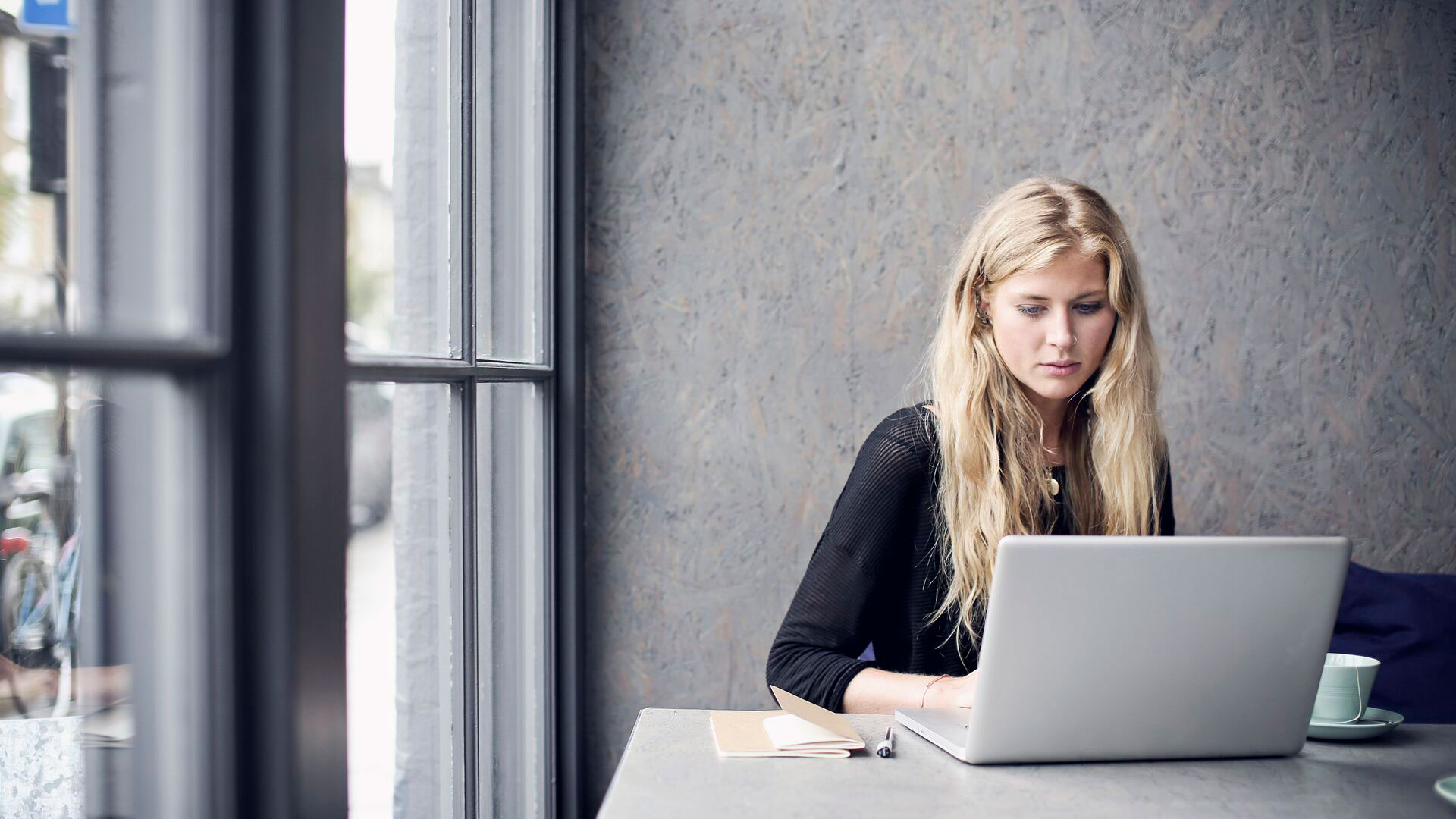 Woman using computer whilst sitting in cafe