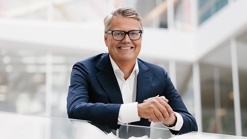 Man i kostym står i en trappa med glasräcken.