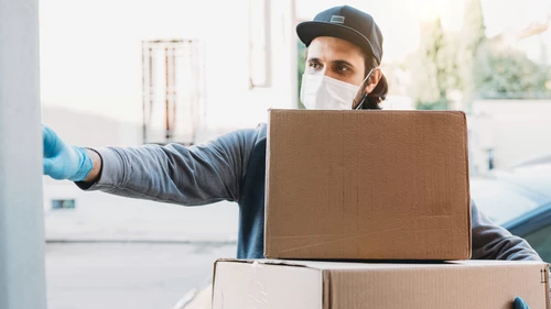 Delivery man is ringing the bell to deliver two cardboard boxes