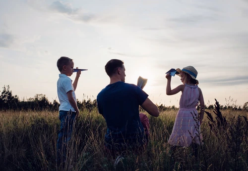 Father playing paper aeroplanes with his children