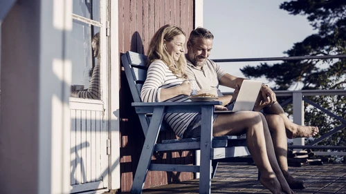 Smiling couple using laptop while having breakfast at porch