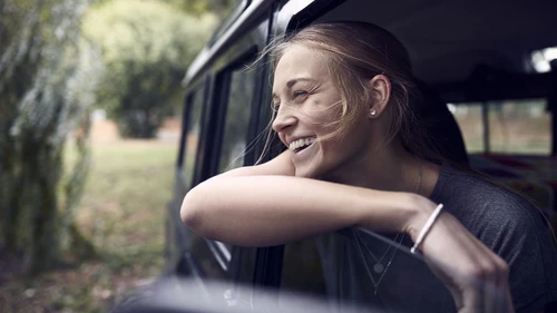 Happy young woman looking out of car window