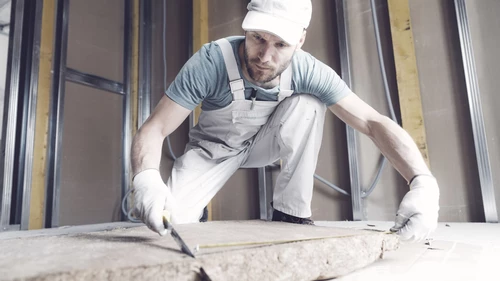 Construction worker cutting mineral rock wool