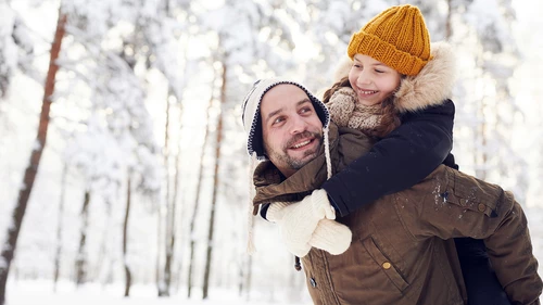 man carrying kid in snow