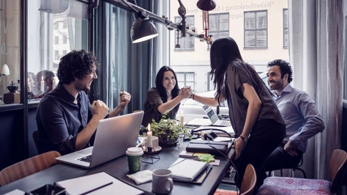 Happy businesswomen holding hands in meeting at creative office