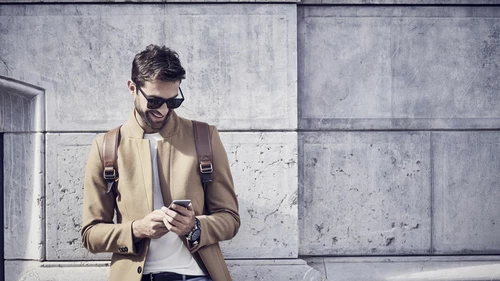 smiling businessman using phone against building