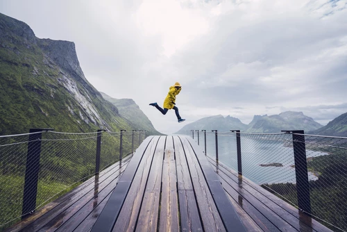 Man jumping on an observation deck at the coast