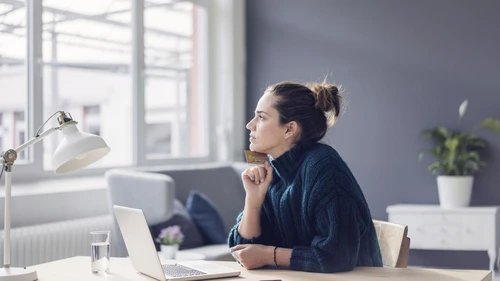 Profile of woman with laptop and credit card looking out the window