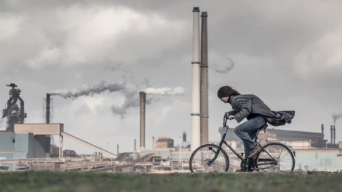 Person-riding-bike-in-front-of-factor