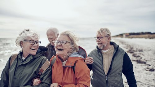 Seniors laughing and walking on the beach