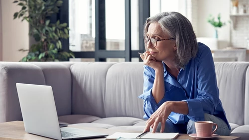 Mature woman watching online webinar on laptop