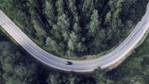 Top-down aerial view of a winding road in the middle of a forest