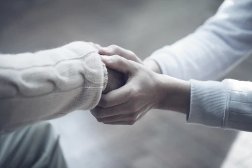 Two persons holding hands