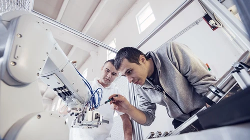 Engineers working on development of automated production line with robotic parts and applied software in order to increase productivity. Precise engineering on electric parts of automated production line.