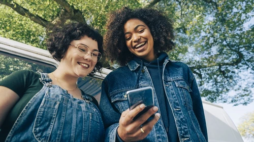 Two young people looking at a mobile phone