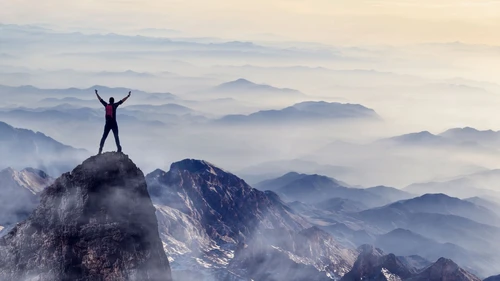 Young man enjoys success on top of a cliff
