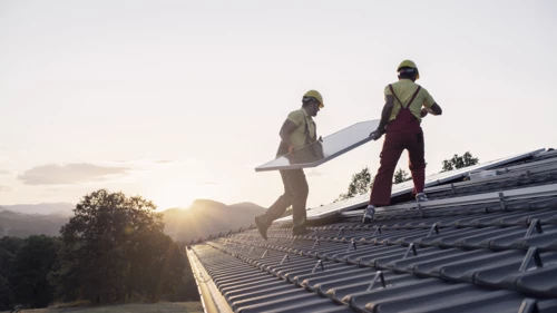 Two men installing solar panels on a roof