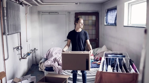 Man carrying cardboard box while standing in bedroom
