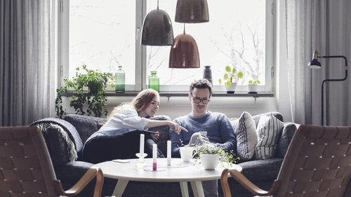 Couple using technologies while sitting on sofa