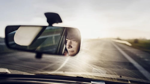 Reflection of a woman in rear view mirror
