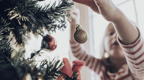 Little girl placing Christmas tree ornament