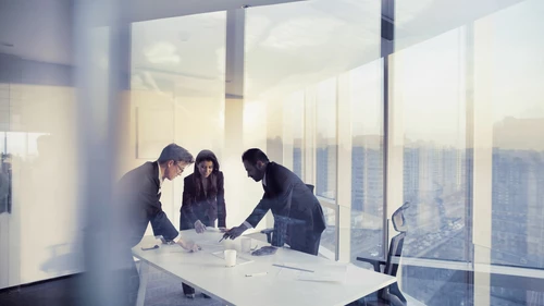 Three people standing and talking a desk