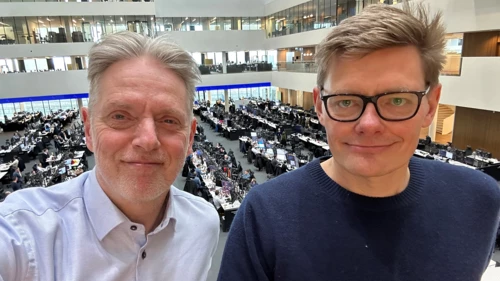 Helge Pedersen and Anders Aalund smiling at the camera. Copenhagen trading floor as a background.