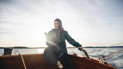 women on sailboat looks at mobile