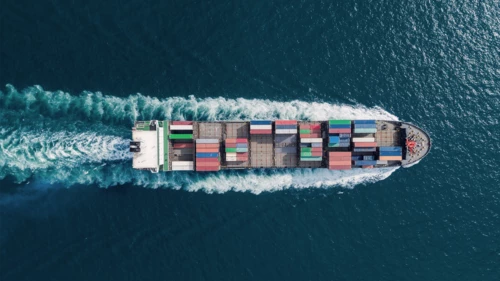 Aerial top view container ship full speed with beautiful wave pattern on the sea for logistics, import export, shipping or transportation