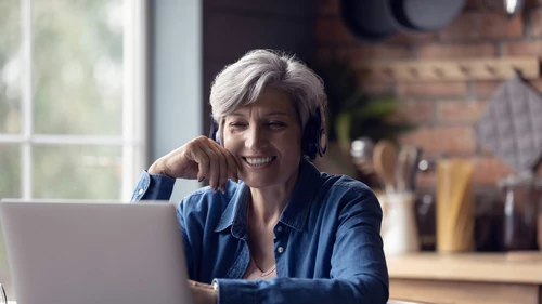 Smart elderly woman watching webinar on laptop