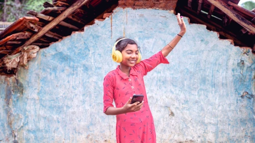 A girl from a tribe in India listening to music with headphones.