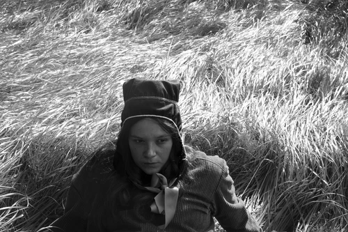 Person wearing Sápmi hat on a grassy field 