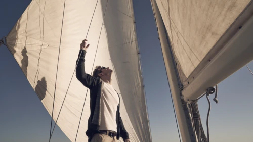 Man looking up at sails while standing on boat