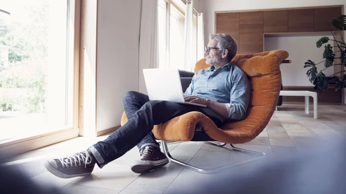 Mature man using laptop in armchair