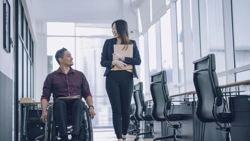 a woman and a man sitting in wheel chair discussing together