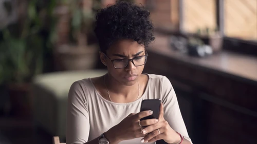 A woman holding cell phone and looking upset