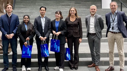 Group of people in business clothes standing in front of a stare case.