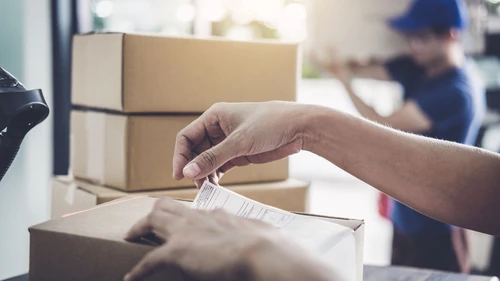 Home delivery service: hands placing shipping label on a box for shipping in e-commerce