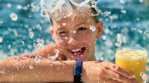 Barn med Nordeas betalarmband i poolen sommarbild. 