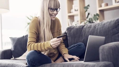 woman sitting on a couch and using laptop