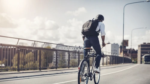 rear-view-of-businessman-riding-bicycle-on-bridge-in-city