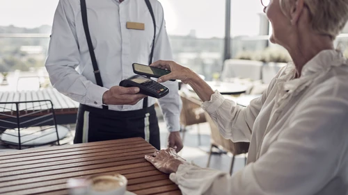 Senior woman paying contactless in cafe